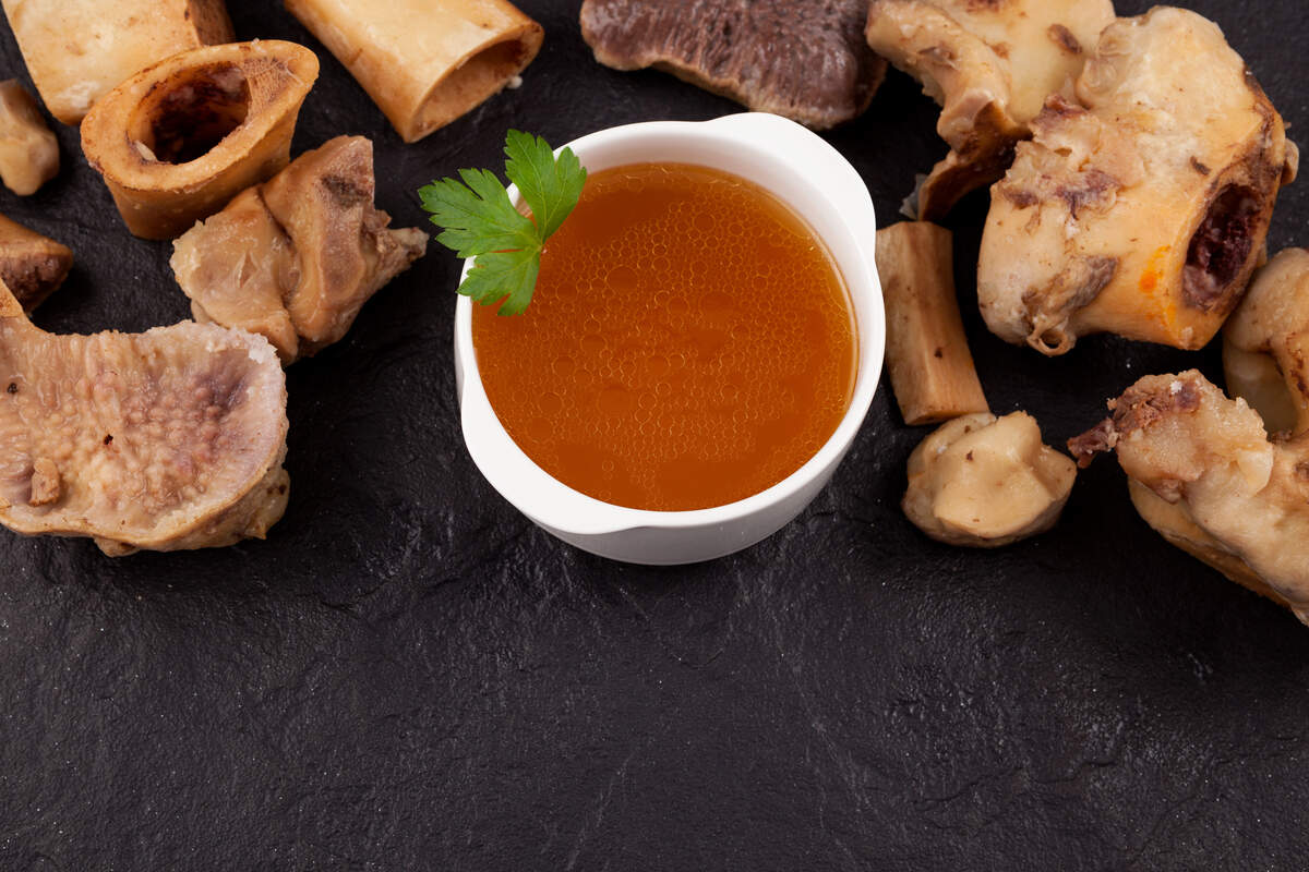 Bone broth on a stone surface next to boiled beef bones.