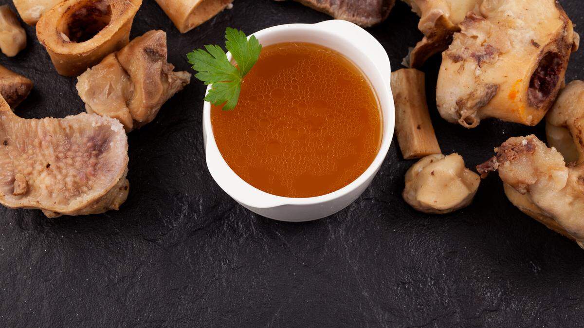 Bone broth on a stone surface next to boiled beef bones. 