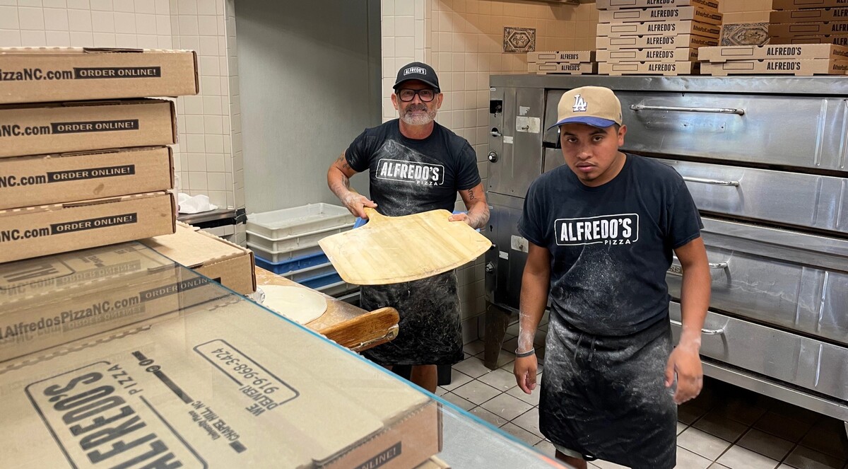 Alfredo Mendes (left) pauses after putting a pizza in the oven at Alfredo’s Pizza Villa in University Place mall. He and his employees were one of the few businesses that remained open after the July 6, 2025, tropical storm.