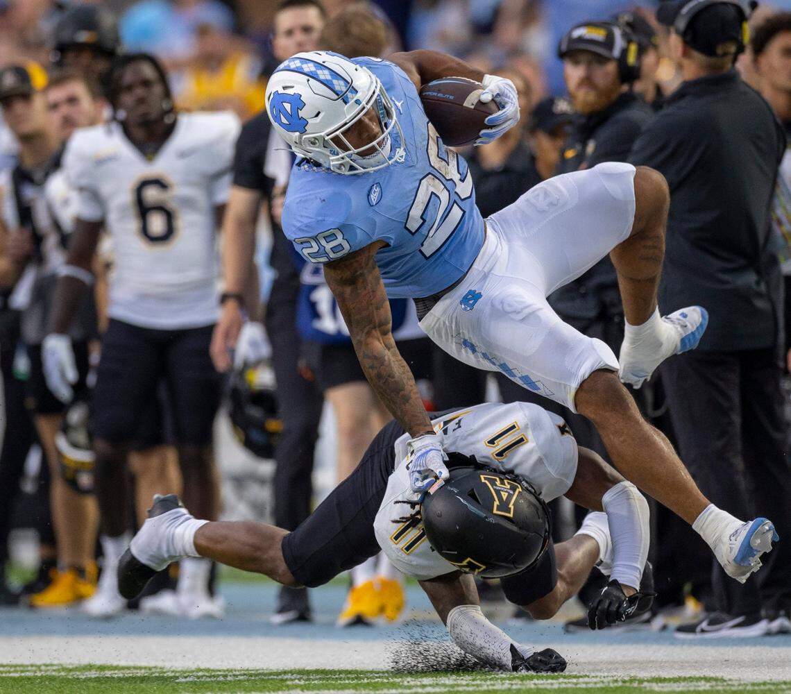 North Carolina running back Omarion Hampton (28) hurdles over Appalachian State’s Jordan Favors (11) after a 31-yard gain in the second quarter on Saturday September 9, 2023 at Kenan Stadium in Chapel Hill, N.C.