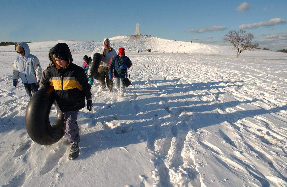 After a couple of hours on the steep slopes at the Wright Brothers Memorial Chris King, foreground, and members of the Robertson family head back to their cars after a winter storm dumped several inches of snow on the region in January 2002.