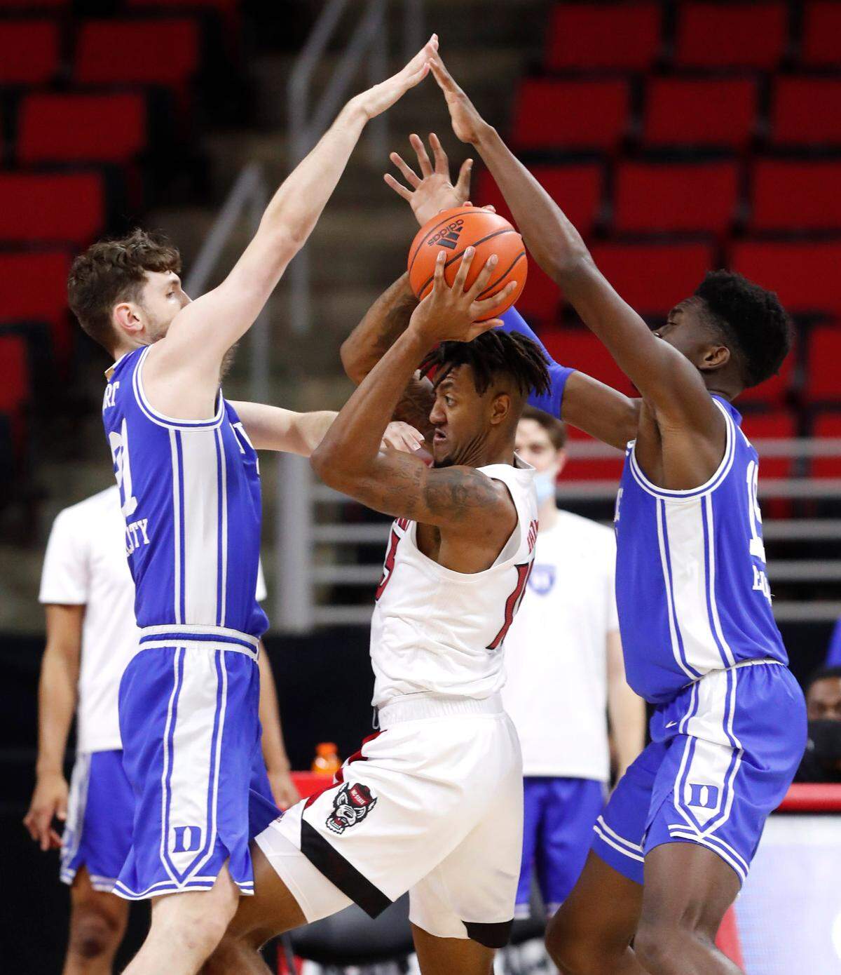 N.C. State’s Manny Bates (15) tries to get out of the pressure by Duke’s Matthew Hurt (21) and Mark Williams (15) during the first half of N.C. State’s game against Duke at PNC Arena in Raleigh, N.C., Saturday, February 13, 2021.