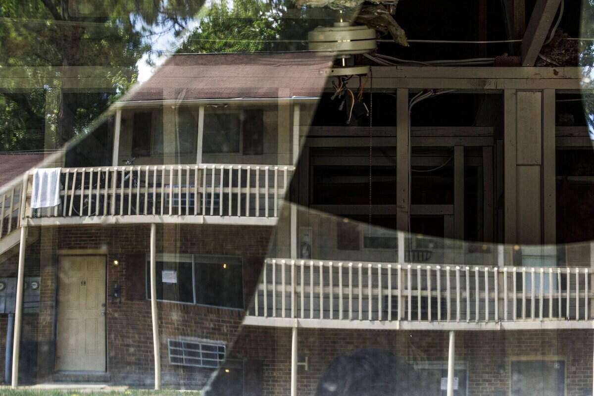 Broken windows reflected views of the Camelot Village housing complex on Thursday, July 2, 2026, in Chapel Hill, North Carolina. A year later, many of the lower-level units remain vacant and damaged.