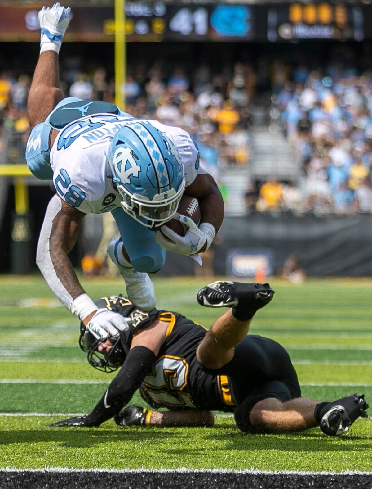 North Carolina’s Omarion Hampton (28) hurdles over Appalachian States Jackson Greene (25) scoring a touchdown on a two-yard run to give the Tar Heels a 49-35 lead in the fourth quarter on Saturday, September 3, 2022 at Kidd Brewer Stadium in Boone, N.C.