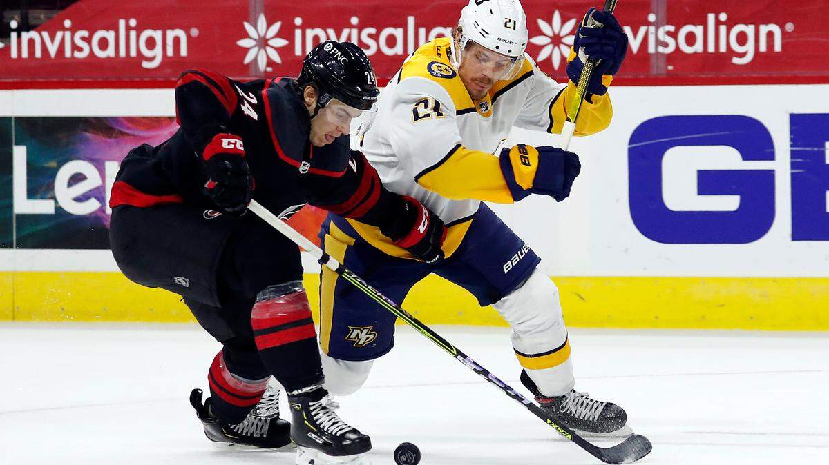 Carolina Hurricanes’ Jake Bean (24) and Nashville Predators’ Nick Cousins (21) compete for the puck during the first period of an NHL hockey game in Raleigh, N.C., Thursday, March 11, 2021. (AP Photo/Karl B DeBlaker)