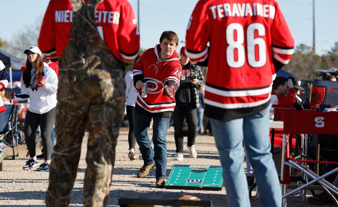 Matthew Skiko plays cornhole with Banks Campbell, left, and Cameron McNabb as they tailgate before the NHL Stadium Series game between the Carolina Hurricanes and the Washington Capitals at Carter-Finley Stadium in Raleigh, N.C., Saturday, Feb. 18, 2023.