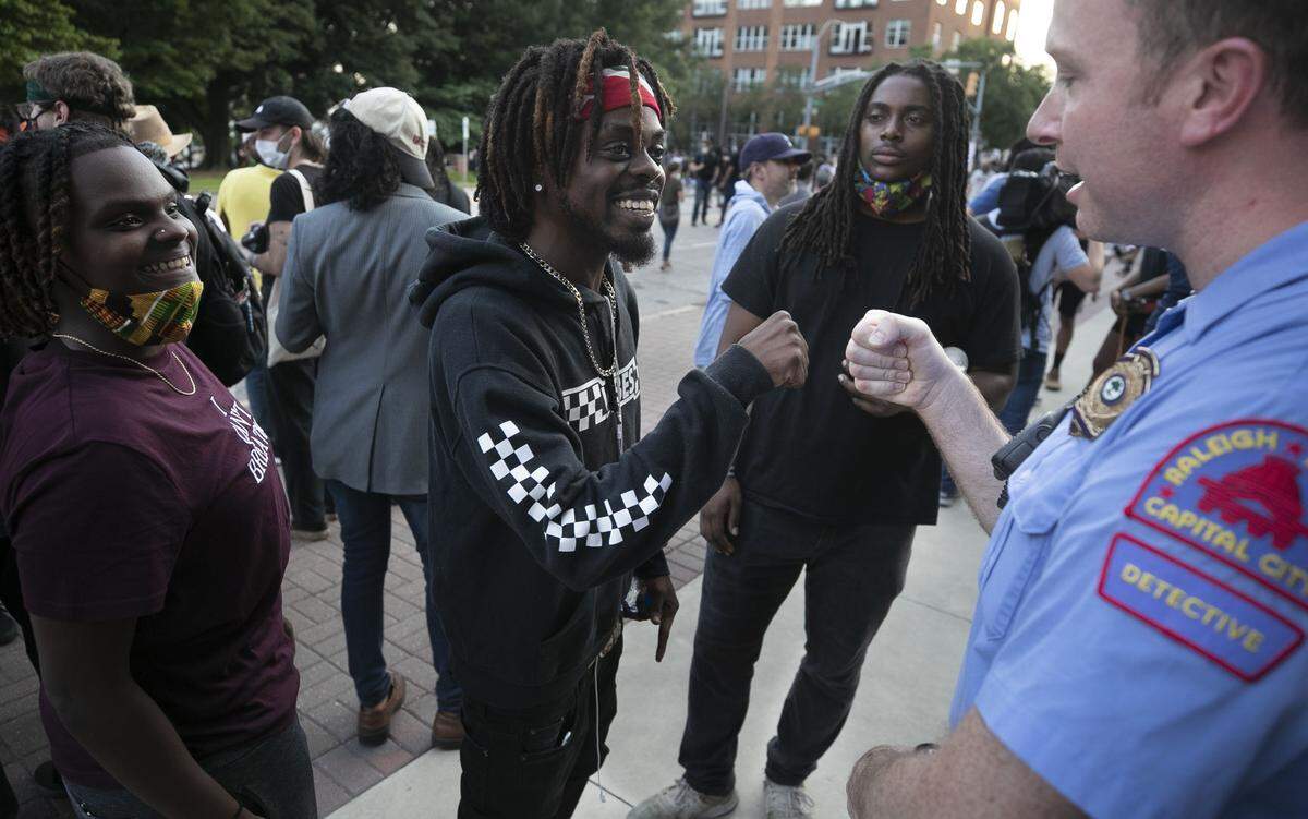 Raleigh Police Detective B.H. Winston, a veteran of 16 years, fist bumps Albert Fervily after having a conversation with Keesh Ormond, left and Dante Robinson following a rally at the Raleigh Municipal Building on Tuesday, June 2, 2020 in Raleigh, N.C.