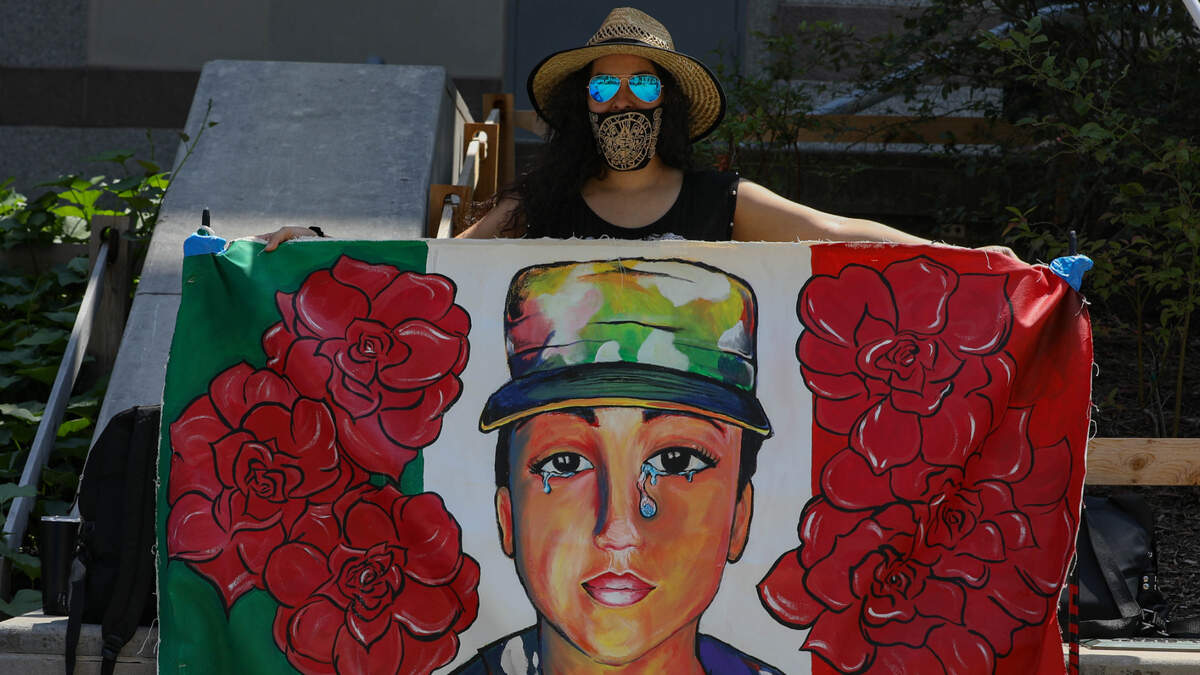 Raleigh resident Veronica Arellano holds up the mural she co-created of Vanessa Guillén, a U.S. Army soldier who was murdered in Fort Hood, Texas. Arellano says her favorite part of the mural is the U.S. flag within the tear streaming down Guillén’s face.