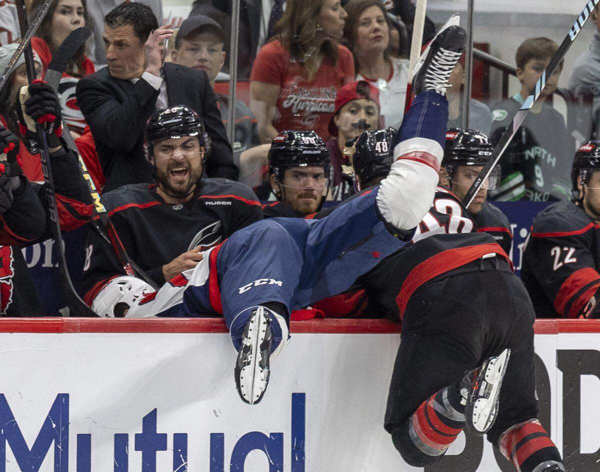 Carolina Hurricanes left wing Jordan Martinook (48) checks Washington Capitols center Connor McMichel (24) into the Hurricanes bench in the first period during Game 3 of their series on Saturday, May 10, 2025 at Lenovo Center in Raleigh, N.C