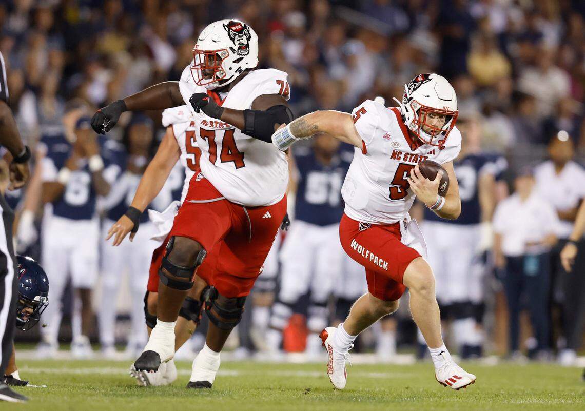 N.C. State quarterback Brennan Armstrong (5) gains yards as offensive lineman Anthony Belton (74) blocks for Armstrong during the first half of N.C. State’s game against UConn at Rentschler Field in East Hartford, Conn. Thursday, August 31, 2023.