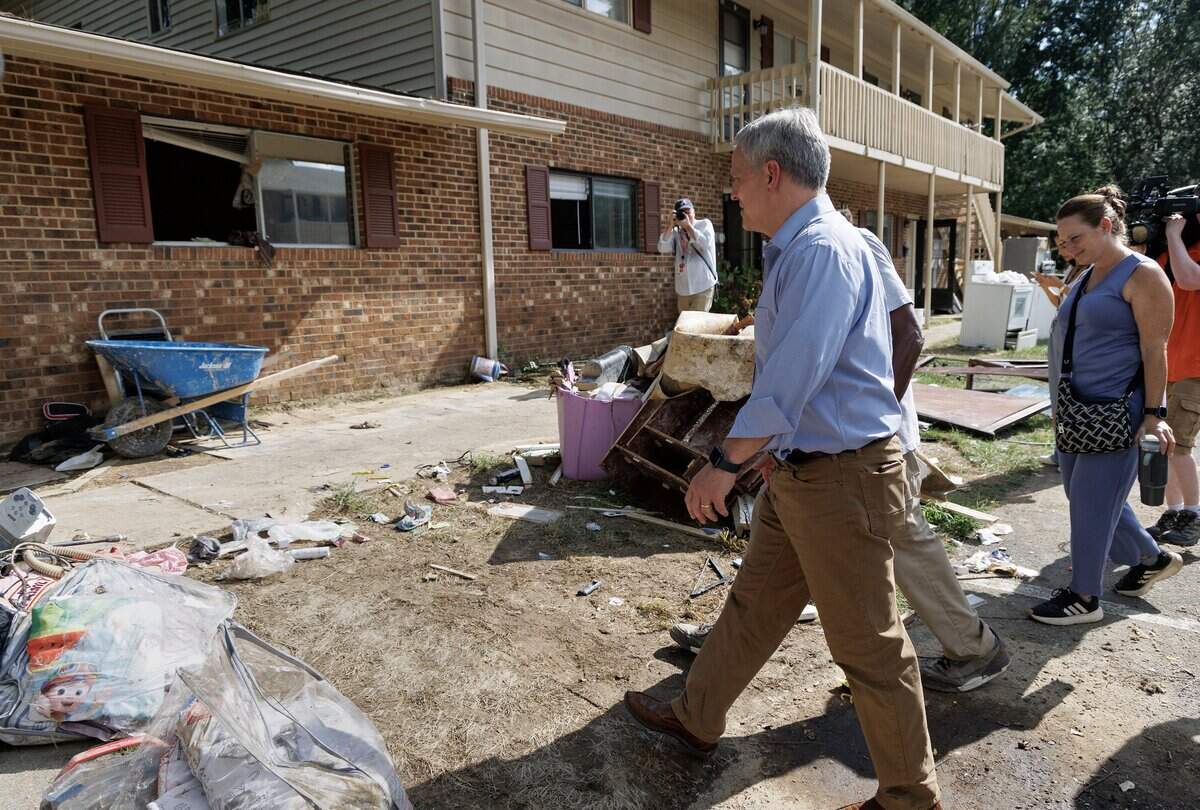 N.C. Gov. Josh Stein walks with Camelot Village resident Shelton Stokes on Friday, July 18, 2025, during a tour of flood damage caused by remnants of Tropical Storm Chantal in Chapel Hill, N.C.
