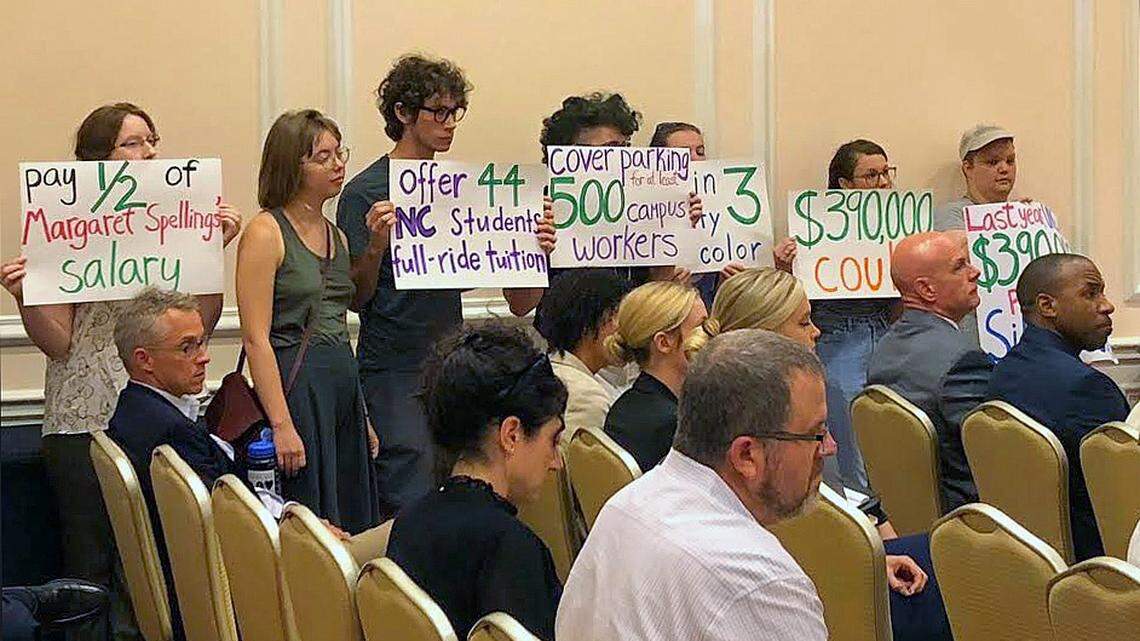 Rrotesters hold signs callling attention to the  $390,000 the university spends on safety around the Silent Sam Confederate monument.
