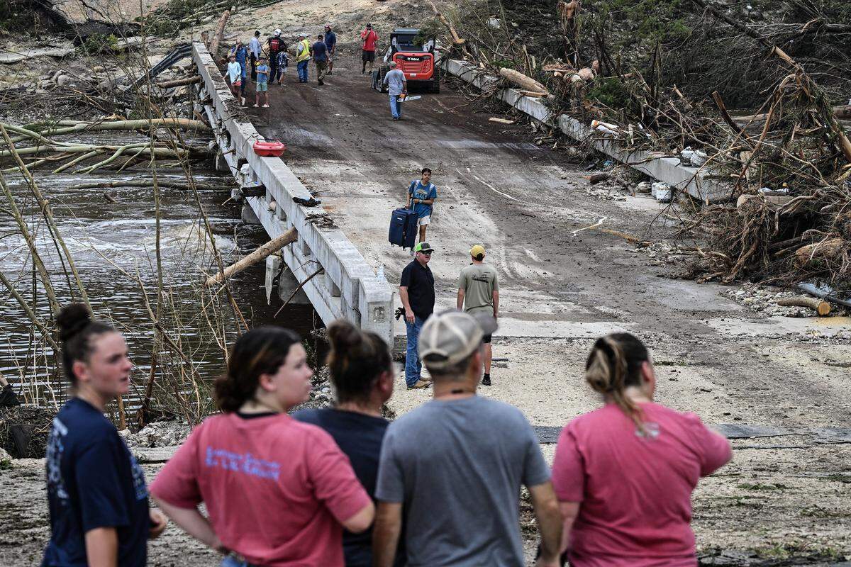 People look on as law enforcement and volunteers search for missing people near Camp Mystic on July 5, 2025. 