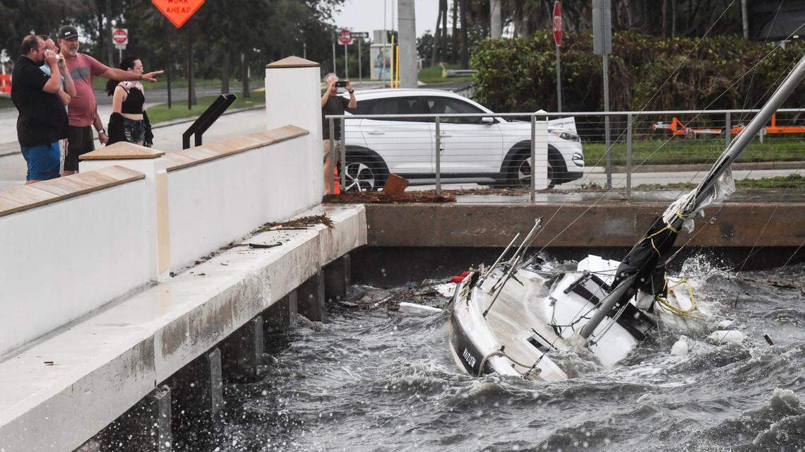 People check out a boat a boat pinned against the seawall in Cocoa‚Äôs Riverfront Park Thursday, September 26, 2024.