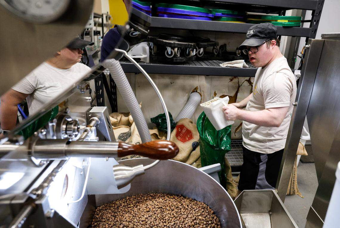 Paul Kocher measures 26 lbs. of coffee beans from Peru to be roasted at the 321 Coffee roasting facility in Raleigh, N.C., Tuesday, June 25, 2024. Reflected to the left is Sophie Pacyna.