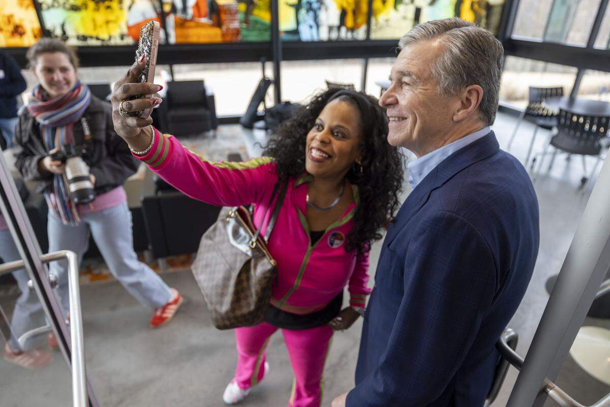 Christina Lahowah Jones stops former NC governor and U.S. Senate candidate Roy Cooper for a selfie opportunity after he cast his ballot at the Chavis Community Center on the first day of early voting in the North Carolina primary, on Thursday, Feb. 12, 2026, in Raleigh, N.C. 