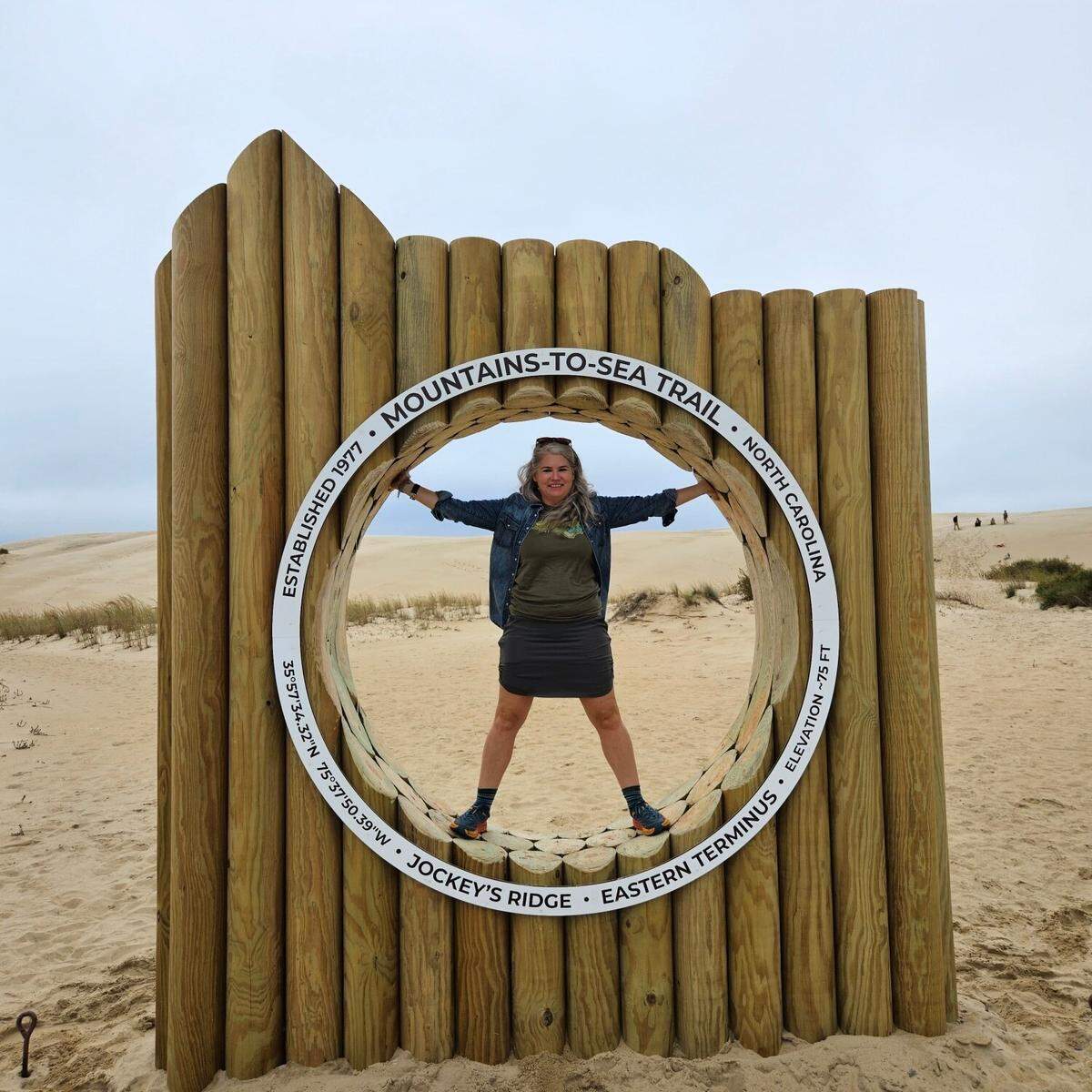 Betsy Brown of the Friends of the Mountains-to-Sea Trail stands in the new monument that marks the beginning and end of the trail in Jockey’s Ridge State Park in Nags Head.