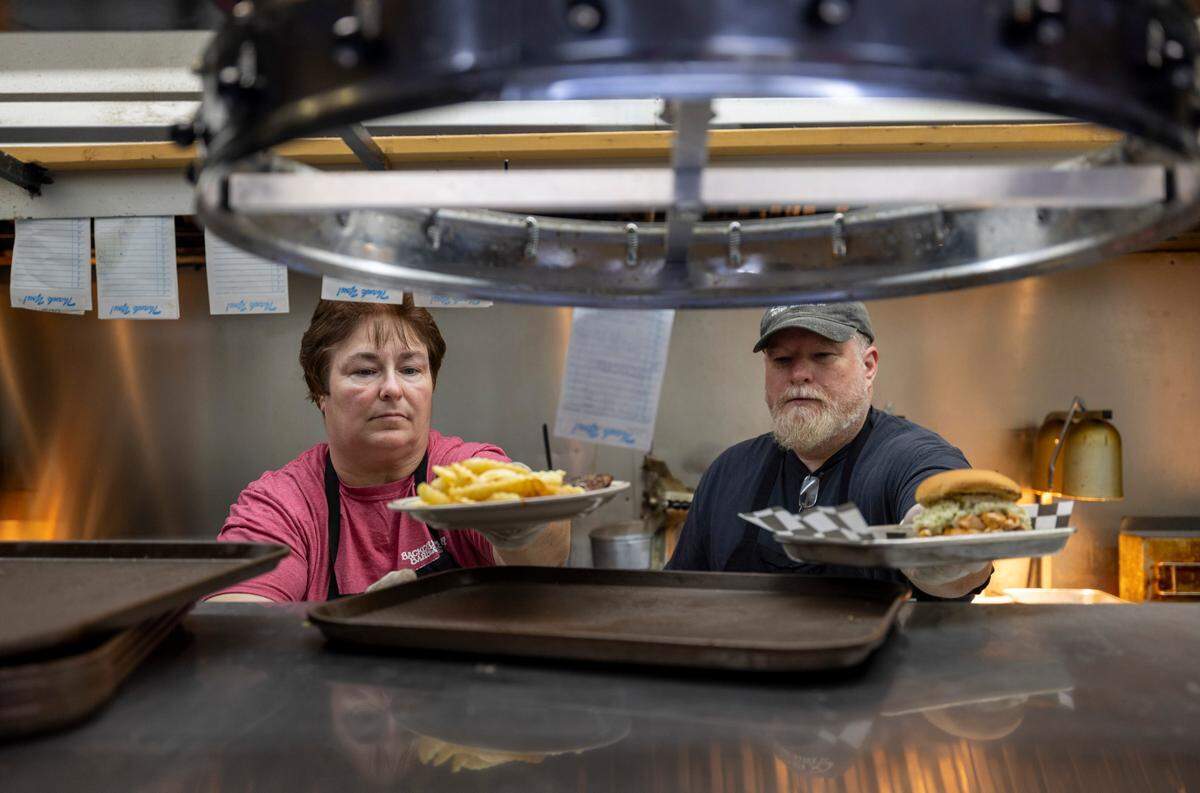 Tina Brogdon and Norman Morrison finish two lunch orders in the kitchen at Backcountry Barbecue on Tuesday, October 10, 2023 in Lexington, N.C.