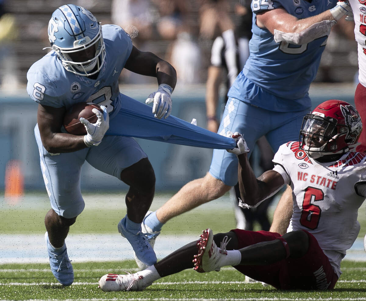 N.C. State’s Jakeen Harris (6) tries to stop North Carolina’s Michael Carter (8) after a 12-yard gain in the third quarter at Kenan Stadium on Saturday, October 24, 2020 in Chapel Hill, N.C.
