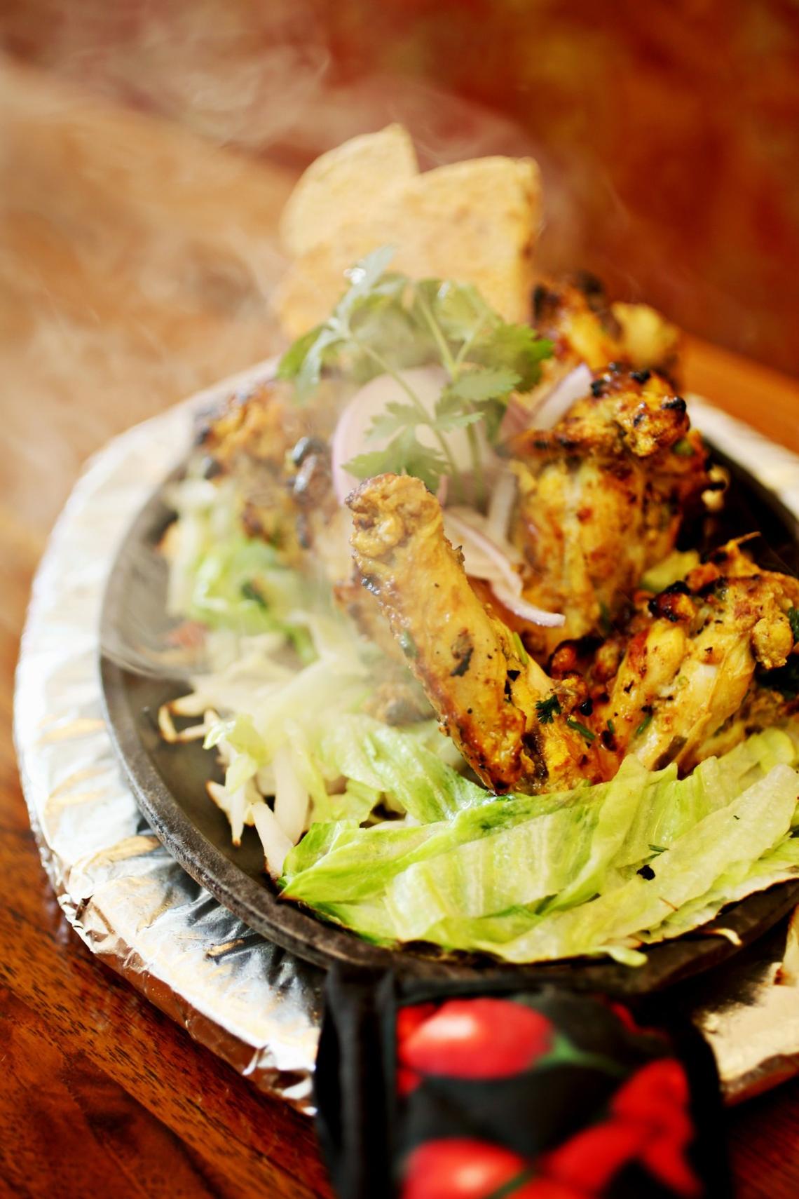 Persis Indian Grill’s Tandoori-grilled Lahsuni Wings are succulent in their char-mottled skins that arrive on a sizzling bed of peppers and onions on a cast iron platter.