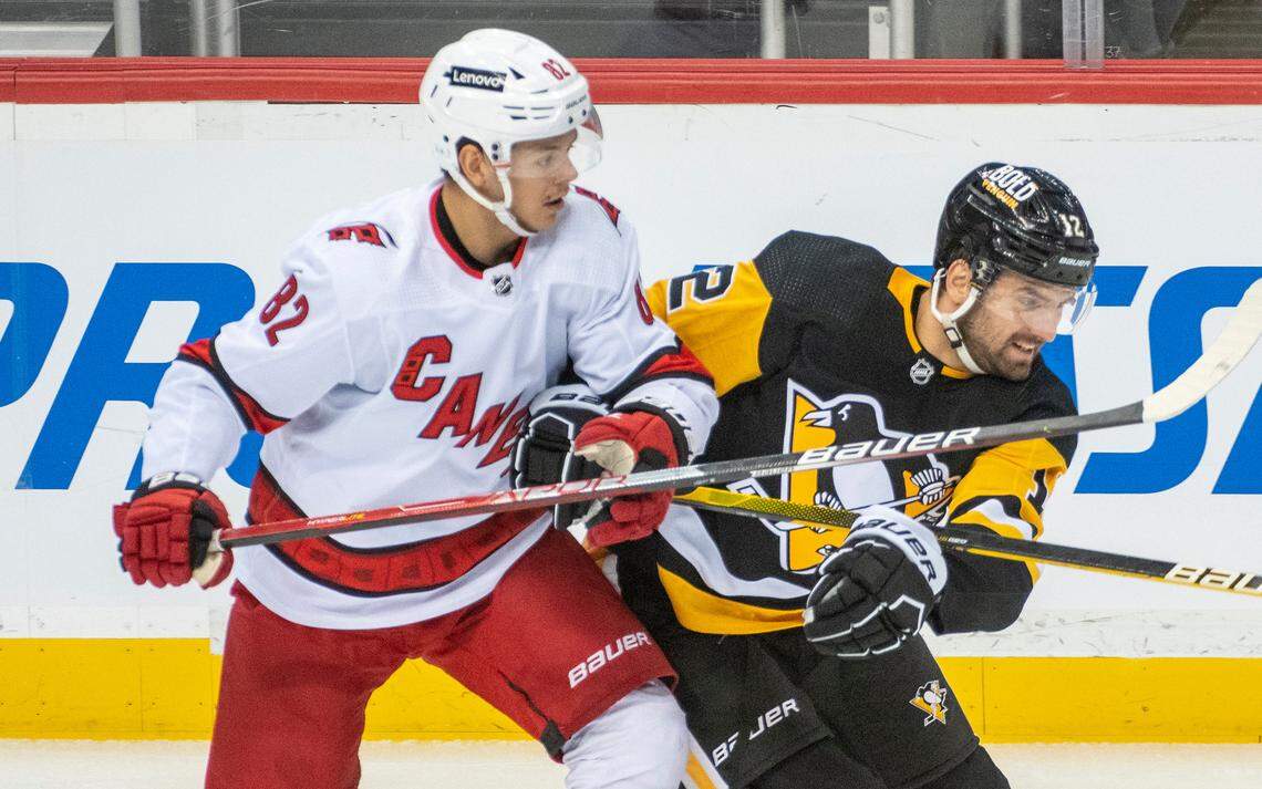 Carolina Hurricanes center Jesperi Kotkaniemi, 82, and Pittsburgh Penguins winger Zach Aston-Reese, 12, battle for position during the first period of an NHL hockey game against the Carolina Hurricanes and Pittsburgh Penguins on Sunday, Feb. 20, 2022, in Pittsburgh. (AP Photo/Fred Vuich)