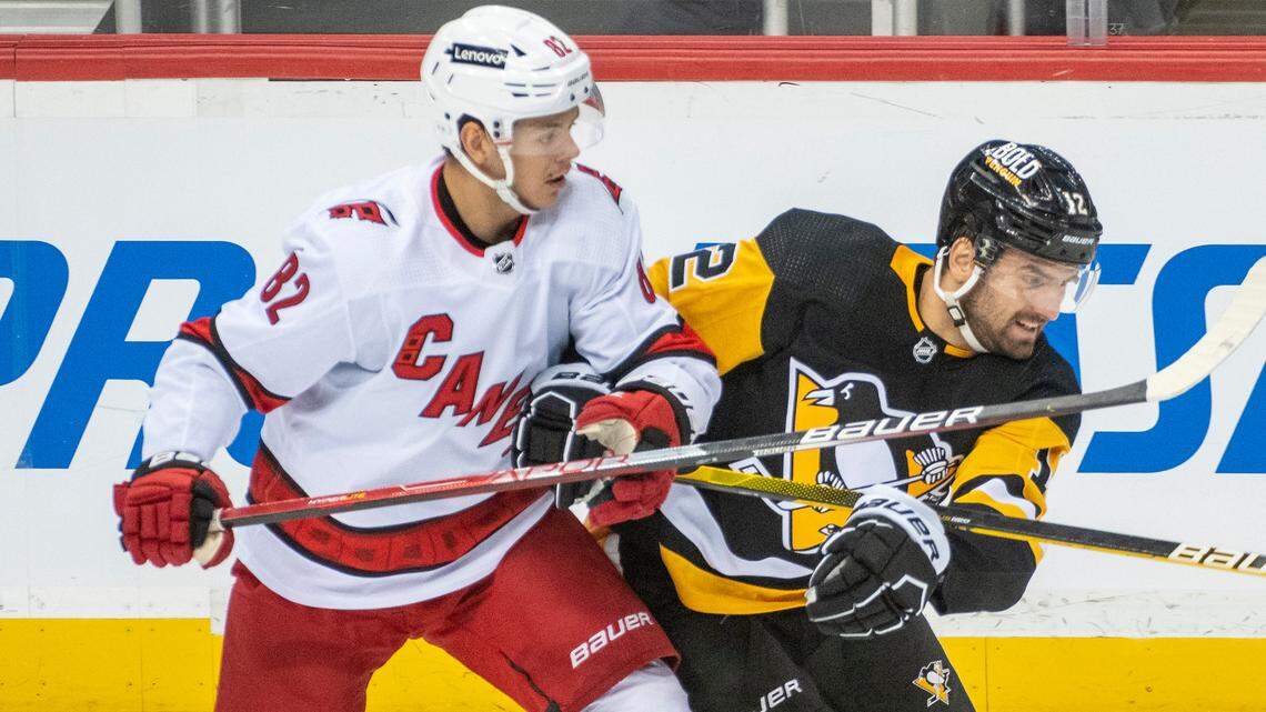 Carolina Hurricanes center Jesperi Kotkaniemi, 82, and Pittsburgh Penguins winger Zach Aston-Reese, 12, battle for position during the first period of an NHL hockey game against the Carolina Hurricanes and Pittsburgh Penguins on Sunday, Feb. 20, 2022, in Pittsburgh. (AP Photo/Fred Vuich)