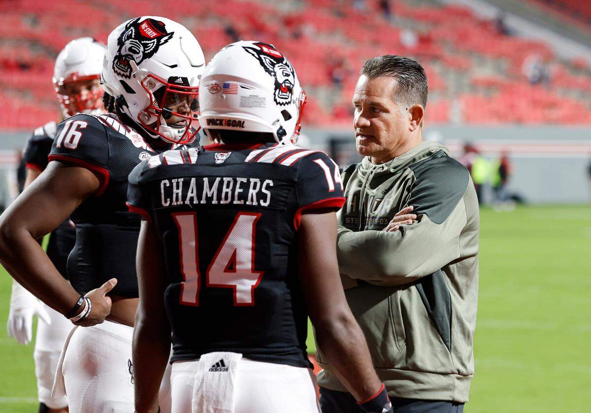 N.C. State offensive coordinator Tim Beck talks with quarterbacks MJ Morris (16) and Jack Chambers (14) as they warm up before N.C. State’s game against Virginia Tech at Carter-Finley Stadium in Raleigh, N.C., Thursday, Oct. 27, 2022.
