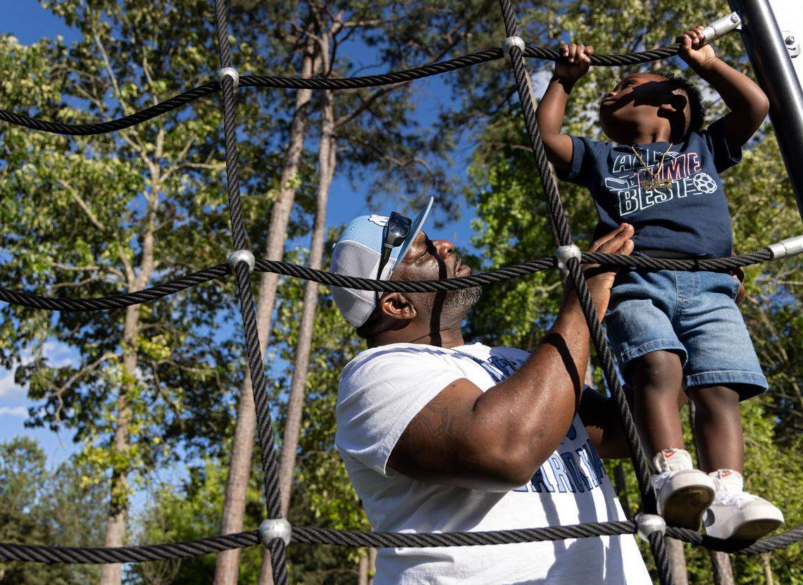 Atari Thomas helps Bryson climb a ropes tower at Barwell Road Park.
