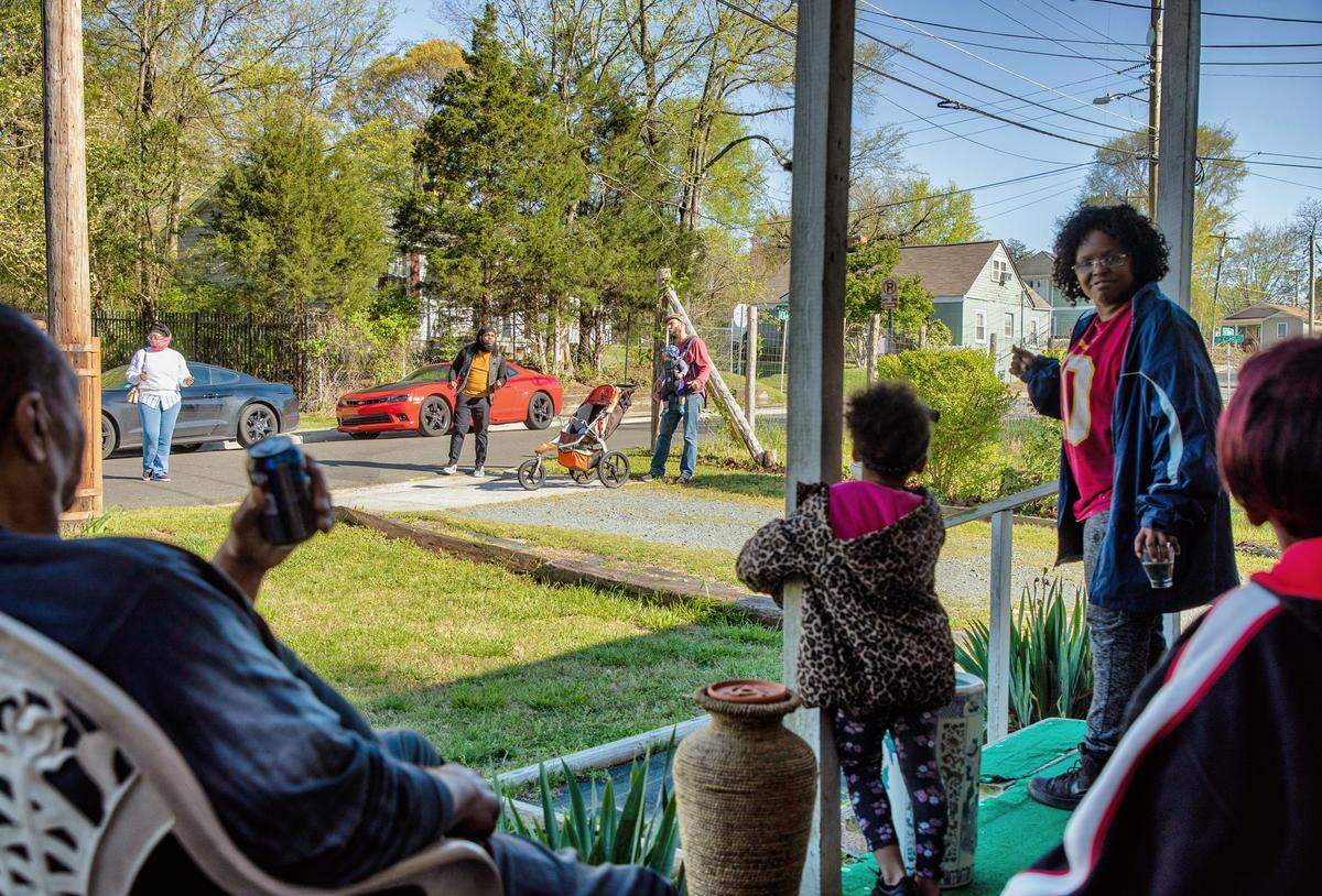 Sada Holman turns to her family and they listen to a group of staff and volunteers from The Marian Cheek Jackson Center for Saving and Making History, from left, Aisha Booze-hall, Brentton Harrison, and Hudson Vaughan, who walked the Northside neighborhood to sing to their neighbors and make sure they were ok, on Thursday, Apr. 2, 2020, in Chapel Hill, N.C.