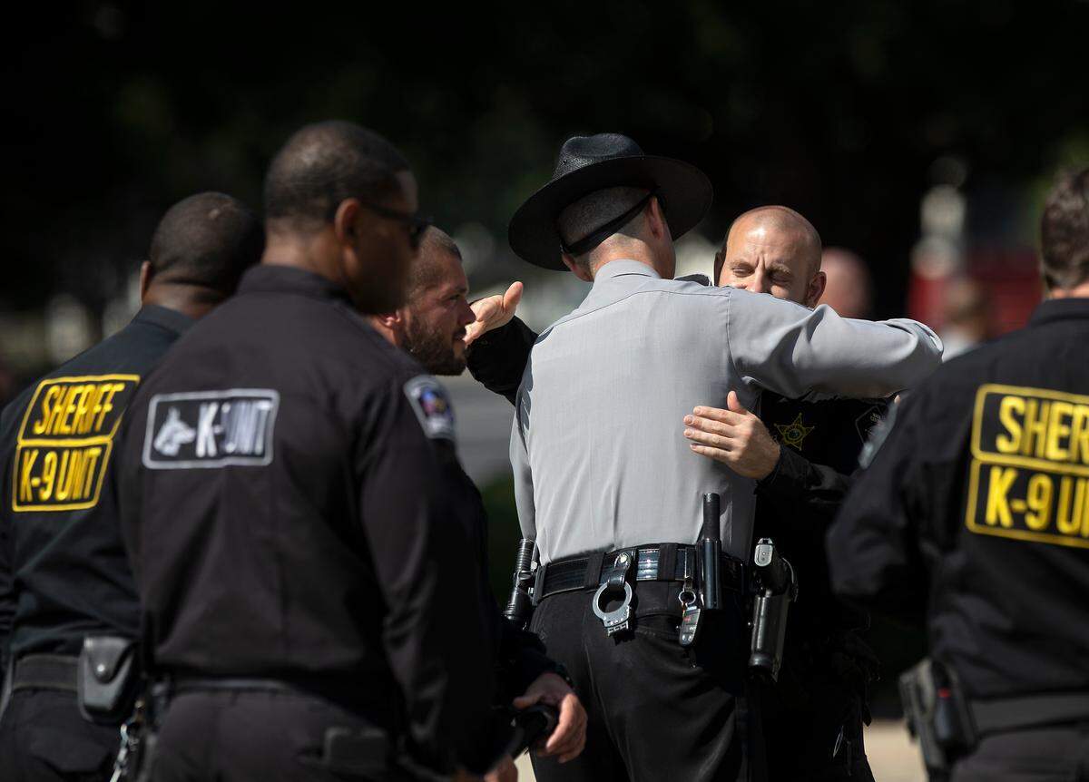 Law enforcement members embrace prior to a memorial service for K9 Santos, a Wake County sheriff’s dog, at the Kerr Scott Building on Wednesday, June 14, 2023, in Raleigh, N.C. K9 Santos, a German shepherd, was accidentally shot and killed by a Knightdale police officer after a traffic stop in May.