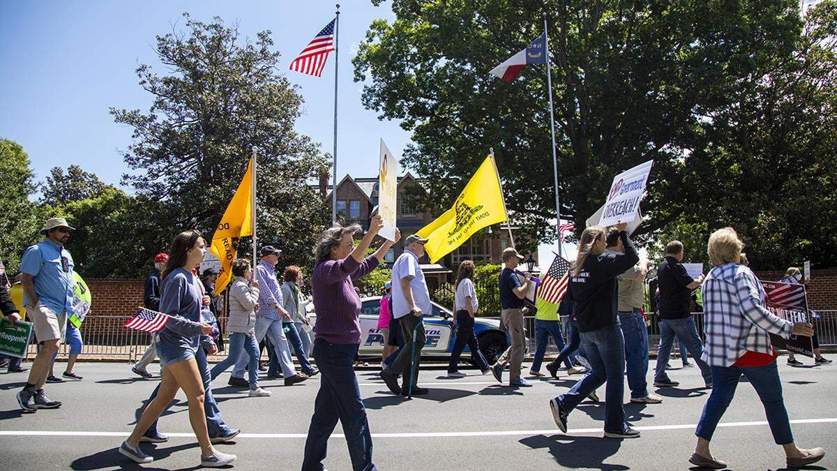 Protesters march in front of the Executive Mansion during a ReOpen NC rally in downtown Raleigh Tuesday, May 12, 2020.