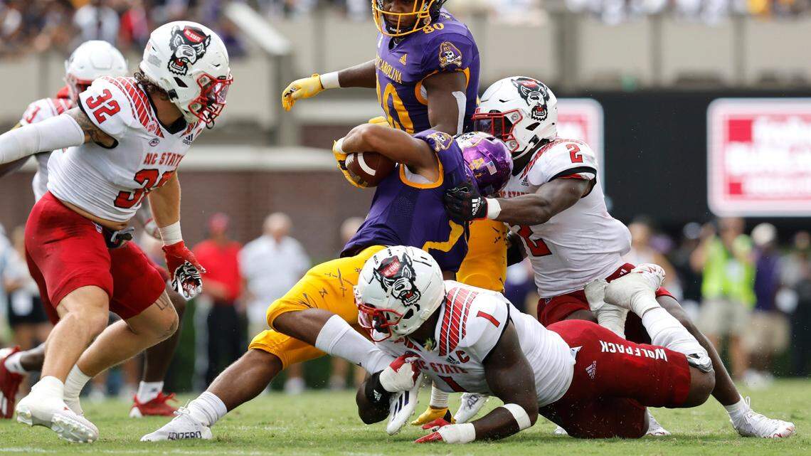 N.C. State linebacker Isaiah Moore (1) tackles East Carolina running back Keaton Mitchell (2) as Drake Thomas (32) and Jaylon Scott (2) close in during the second half of N.C. States 21-20 victory over ECU at Dowdy-Ficklen Stadium in Greenville, N.C., Saturday, Sept. 3, 2022.