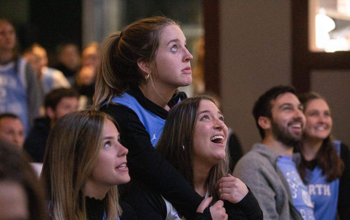 Emily Holler leans onto her friend and fellow UNC-Chapel Hill alum Avery Snoddy while they watch the Tar Heels face off with the Duke Blue Devils in a historic Final Four game at Top of the Hill in Chapel Hill, N.C. on Saturday, April 2, 2022.
