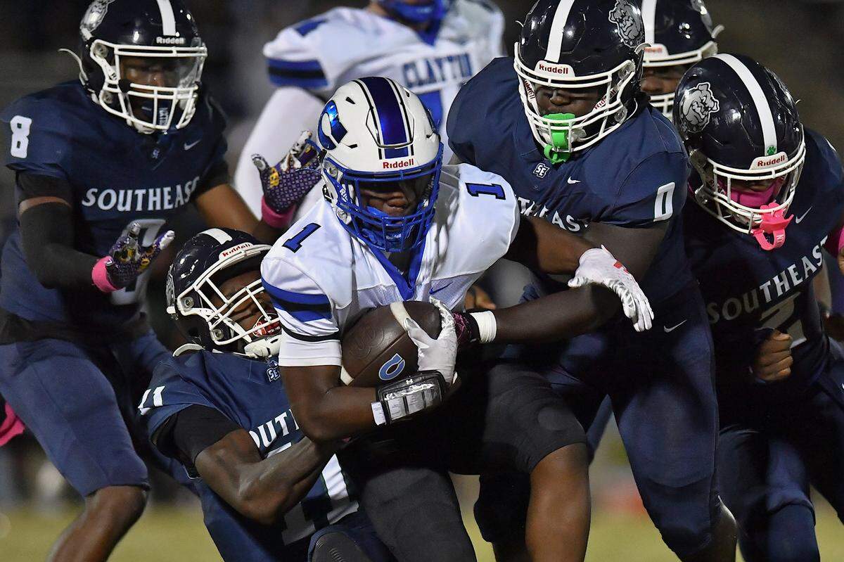 Southeast Raleigh defensive end Keysaun Eleazer (11) and linebacker J'Siah Harden (0) grapple Clayton running back Noah Smith (1) during the first half. The Southeast Raleigh Bulldogs and the Clayton Comets met in a conference football game in Raleigh, N.C. October 3, 2025