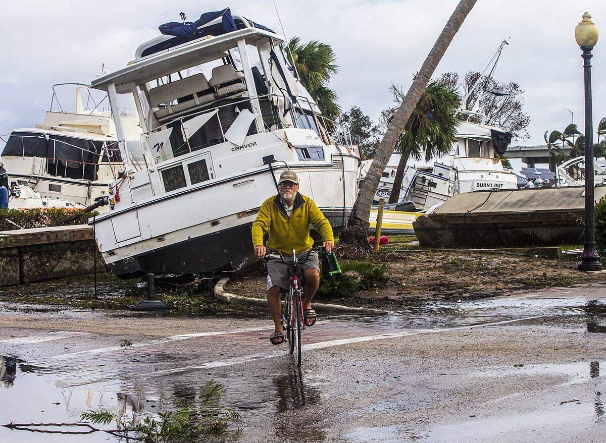A biker rides byfboats that were run aground in the Legacy Harbour Marina in Fort Myers a day after Hurricane Ian hits the West Coast of Florida as Category 4 storm, on Thursday September 29, 2022