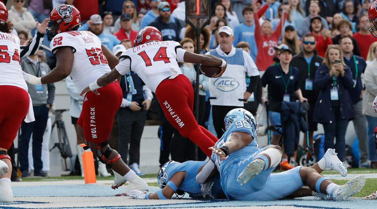 N.C. State quarterback Jack Chambers (14) beats North Carolina defensive back Cam’Ron Kelly (9) to score on a two-yard touchdown run during the first half of N.C. State’s game against UNC at Kenan Stadium in Chapel Hill, N.C., Friday, Nov. 25, 2022.