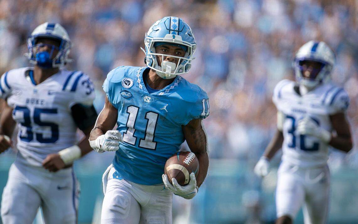 North Carolina’s Josh Downs (11) scores on a 63-yard pass reception from quarterback Sam Howell ahead of Duke’s Dorian Mausi (35) and Jalen Alexander (32) and in the fourth quarter on Saturday, October 2, 2021 at Kenan Stadium in Chapel Hill, N.C.