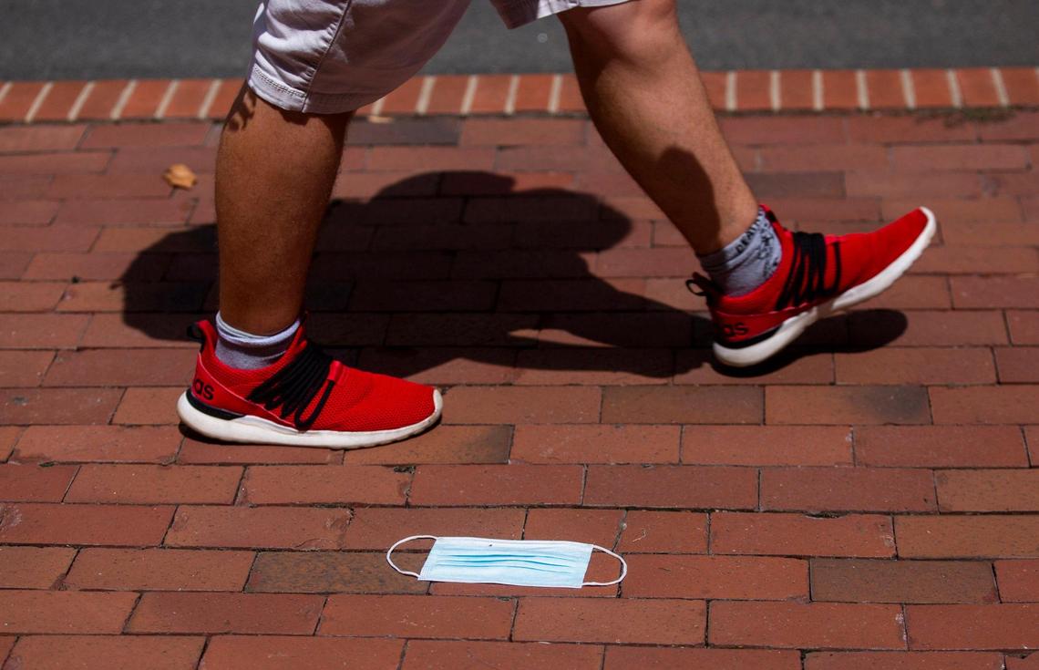 N.C. State students walk past a lost mask on the sidewalk, on the first day of classes for the fall semester, on Monday, Aug. 16, 2021, in Raleigh, N.C.
