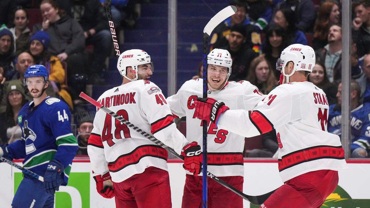 Carolina Hurricanes’ Jesper Fast (71), of Sweden, celebrates his goal with teammates Jordan Martinook (48) and Jordan Staal (11) as Vancouver Canucks’ Kyle Burroughs (44) skates to the bench during the third period of an NHL hockey game in Vancouver, British Columbia, Monday, Oct. 24, 2022. (Darryl Dyck/The Canadian Press via AP)
