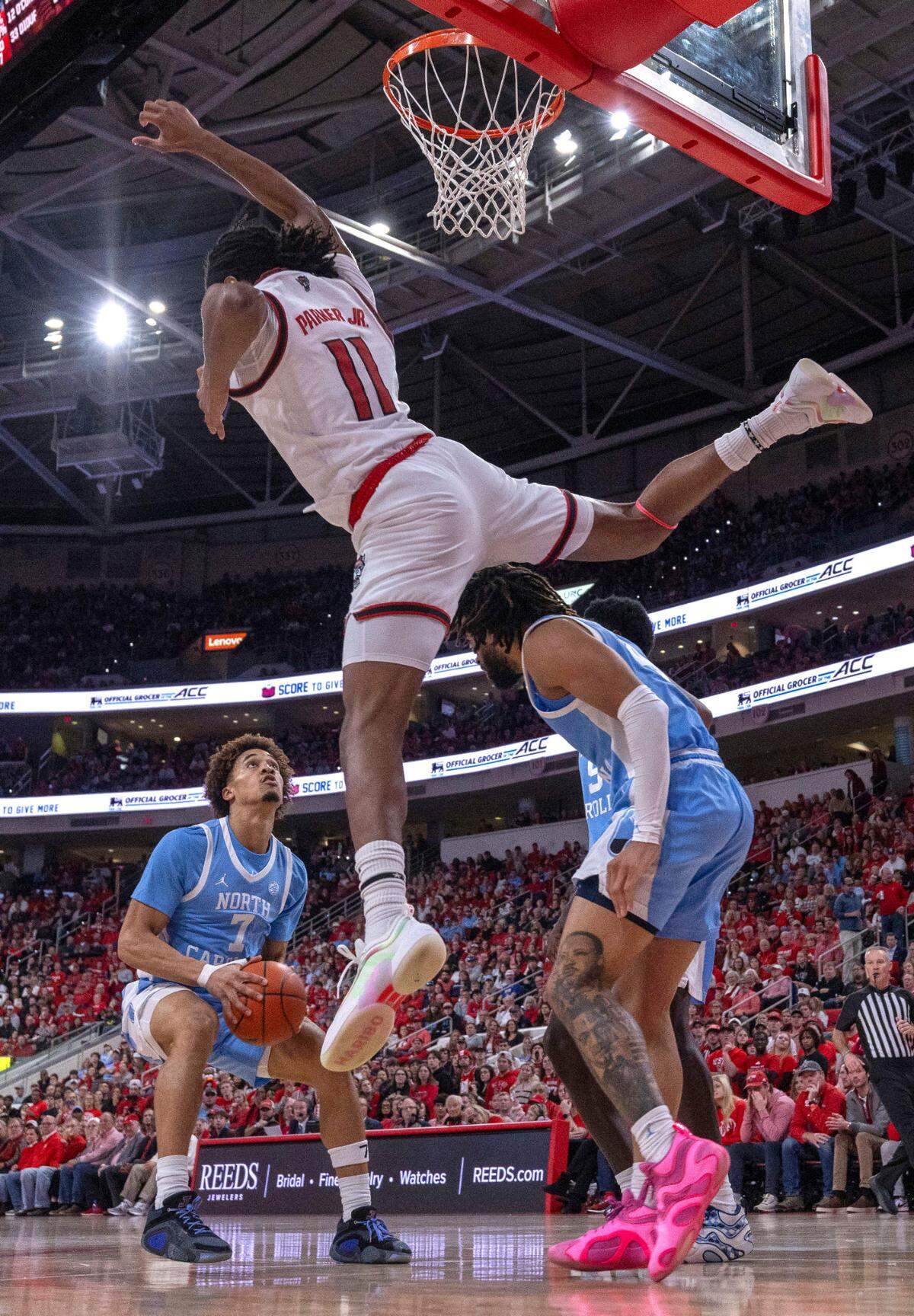 N.C. State’s Dennis Parker Jr. (11) jumps over North Carolina guard R. J. Davis (4) to defend Seth Trimble (7) during the second half on Saturday, January 11, 2025 at Lenovo Center in Raleigh, N.C.