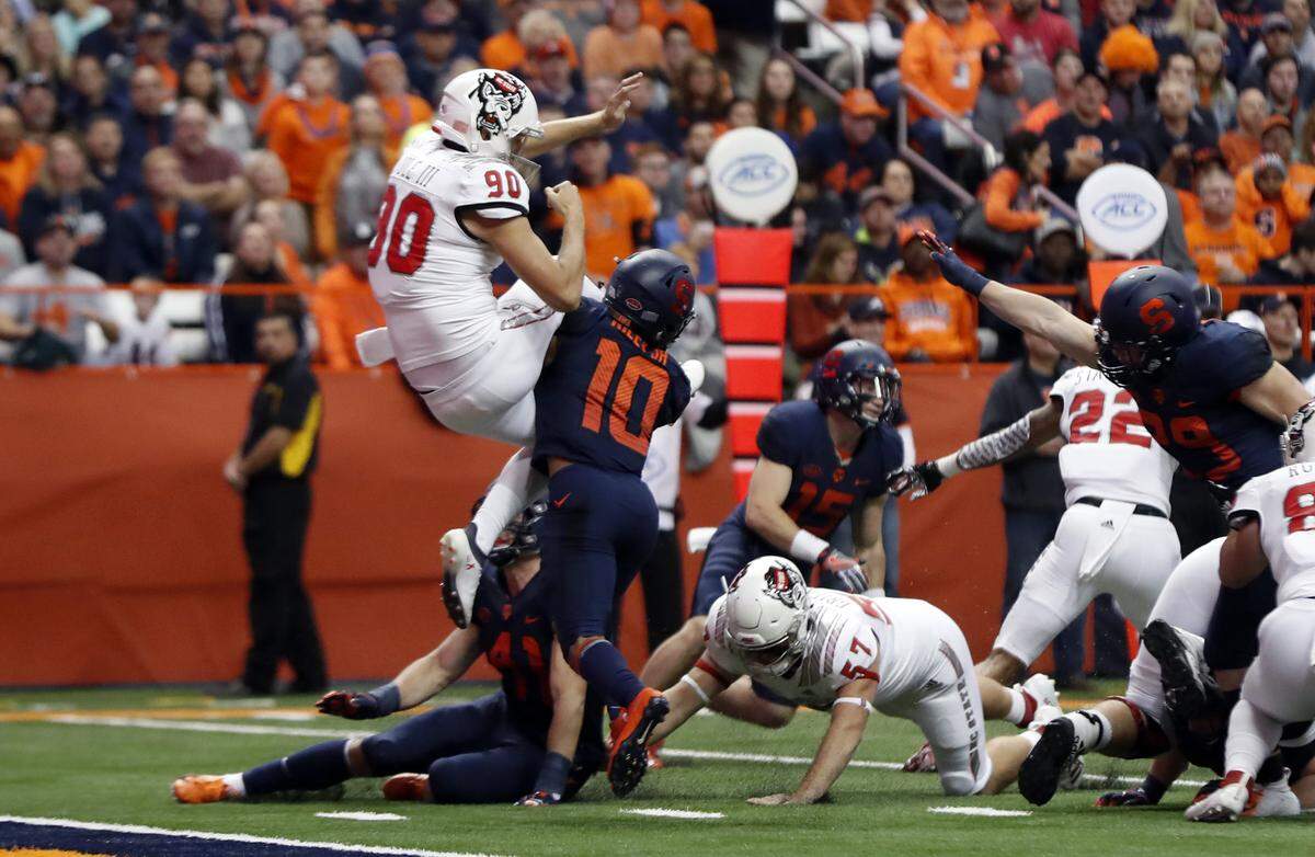Syracuse’s Sean Riley (10) hits N.C. State punter A.J. Cole III (90) as he kicks during the first half of N.C. State’s game against Syracuse at the Carrier Dome in Syracuse, N.Y., Saturday, Oct. 27, 2018. Riley was called for roughing the punter.