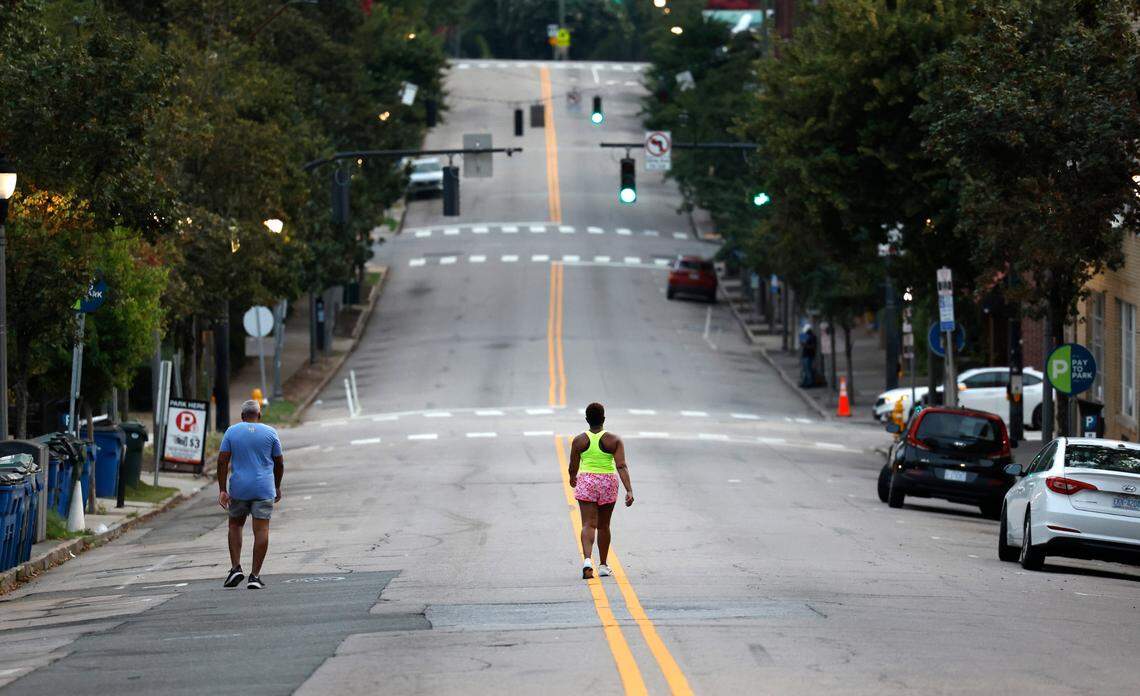 At 6:22 a.m. Saturday, July 22, 2023, walkers head up Glenwood Avenue in the Glenwood South neighborhood of Raleigh, N.C.