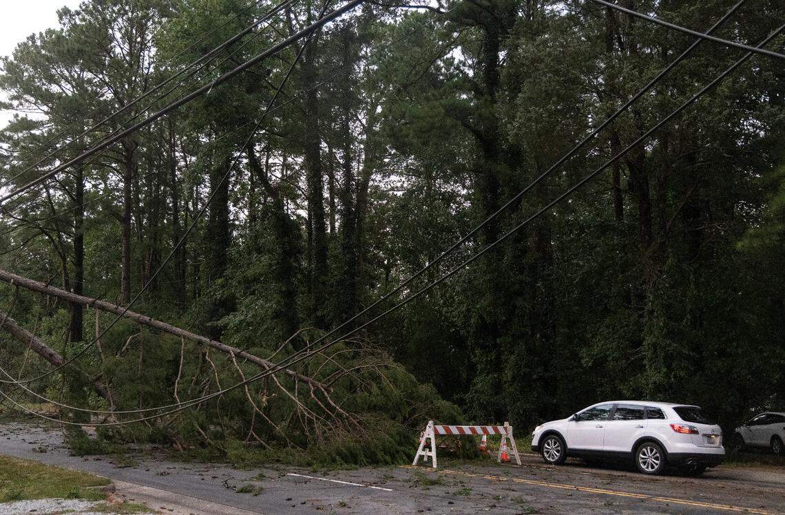 A vehicle navigates around a downed tree on Cole Mill Road following strong storms in Durham, N.C. on Tuesday, Aug. 15, 2023.