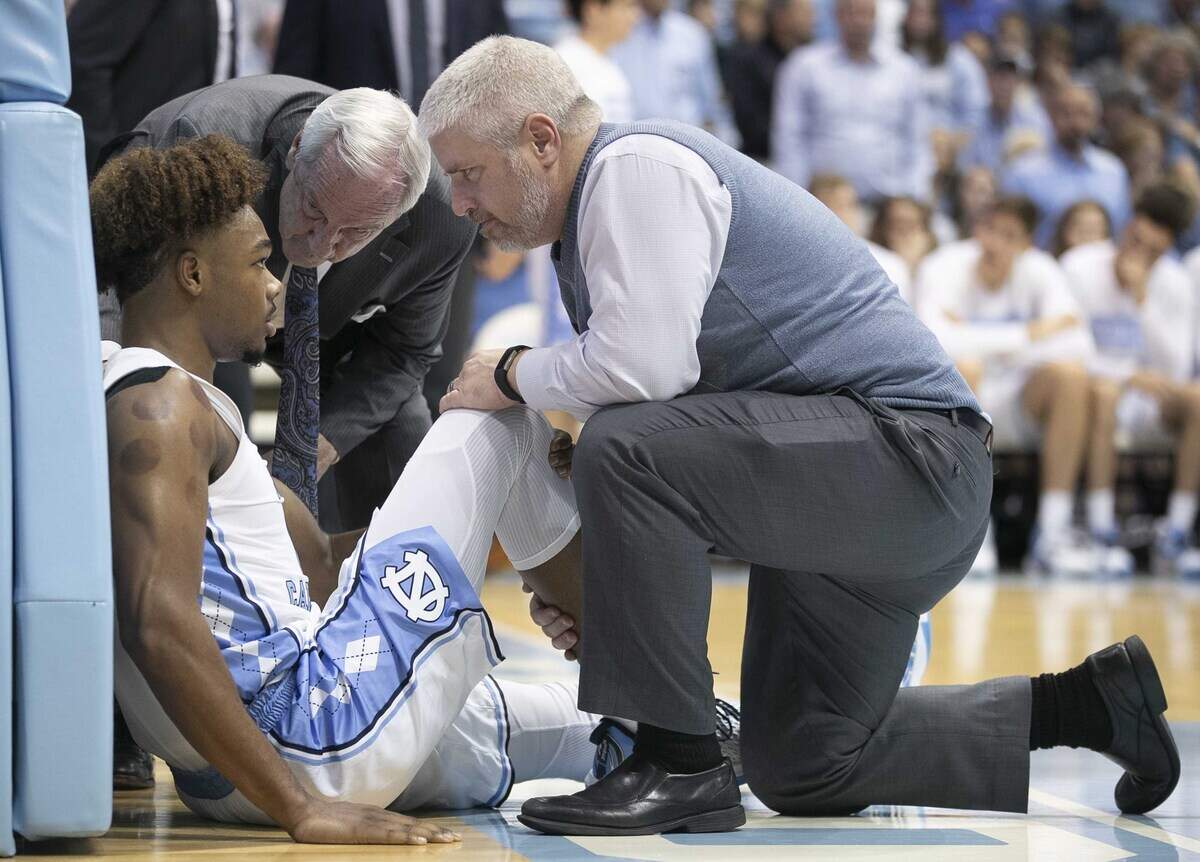 North Carolina coach Roy Williams and trainer Doug Halverson check on Anthony Harris (0) after he injured is right knee in the second half against Yale on Monday, December 30, 2019 at the Smith Center in Chapel Hill, N.C.