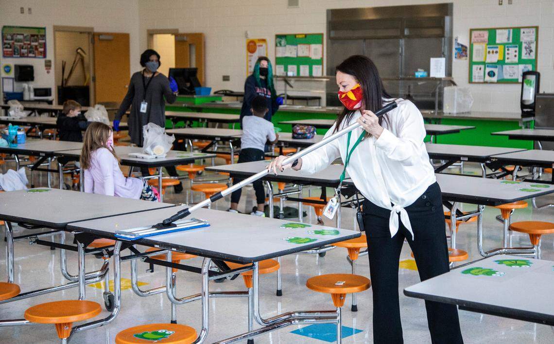 Lisa Brown, principal of Green Elementary School, sanitizes cafeteria tables, March 15, 2021 at the Raleigh school.