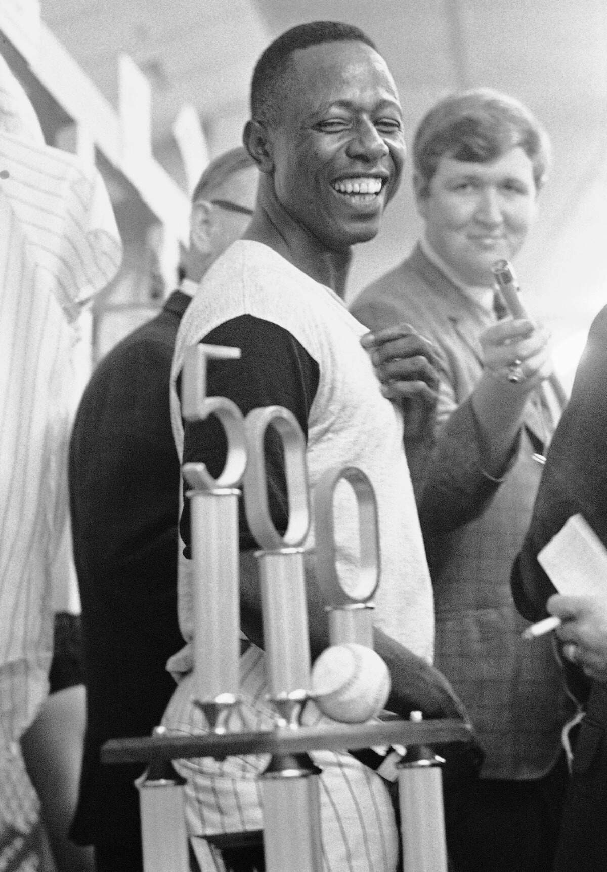 In this July 14, 1968, file photo, Atlanta Braves’ Hank Aaron smiles as he looks at the trophy presented him by Braves President Bill Bartholomay, after Aaron hit his 500th career home run in Atlanta. Hank Aaron, who endured racist threats with stoic dignity during his pursuit of Babe Ruth but went on to break the career home run record in the pre-steroids era, died early Friday, Jan. 22, 2021. He was 86. The Atlanta Braves said Aaron died peacefully in his sleep. No cause of death was given.