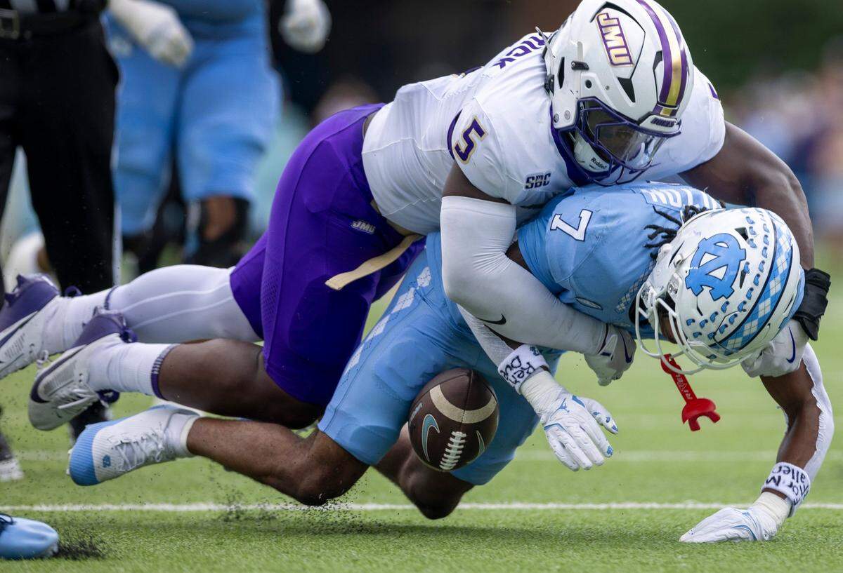 James Madison linebacker Trent Hendrick (5) forces a turnover by North Carolina wide receiver Christian Hamilton (7) in the first quarter on Saturday, September 21, 2024 at Kenan Stadium in Chapel Hill, N.C.