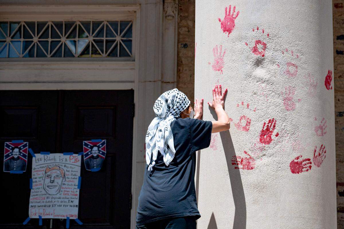 A pro-Palestine protester puts red handprints on South Building on Saturday, May 11, 2024.