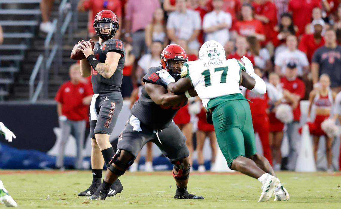 N.C. State center Grant Gibson (50) blocks South Florida defensive tackle Blake Green (17) as quarterback Devin Leary (13) looks for receivers downfield during the Wolfpack’s game against USF at Carter-Finley Stadium in Raleigh, N.C., Thursday, Sept. 2, 2021.