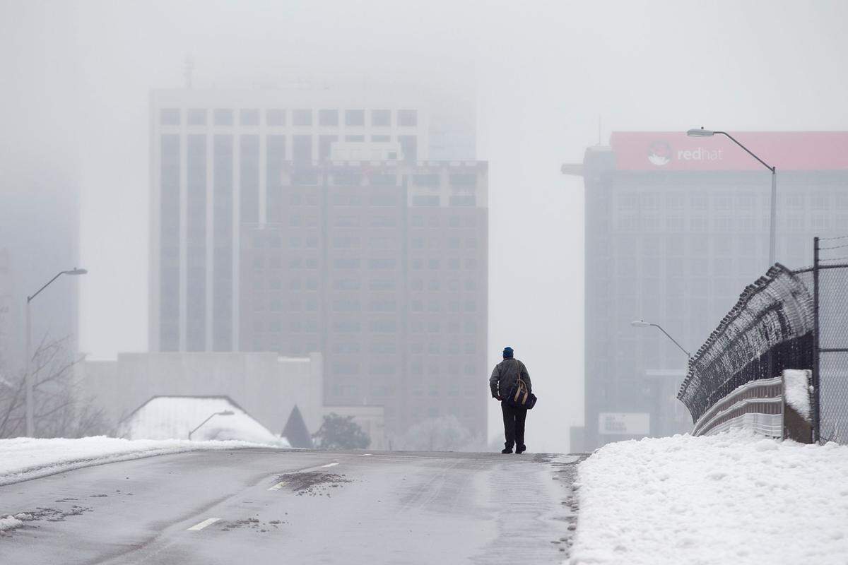 Downtown Raleigh is covered in dense clouds during day two of a winter storm as a man walks across the Wilmington Street bridge on Thursday morning February 13, 2014 in Raleigh, N.C.